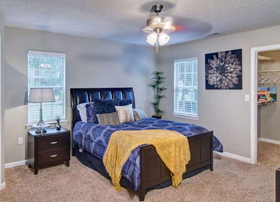 A bedroom with a bed, nightstand, and a ceiling fan at Huntington Chase Apartments, Warner Robins