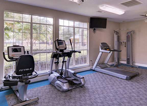 A home gym with a treadmill, elliptical trainer, and a rowing machine at Huntington Chase Apartments, Warner Robins, 31088