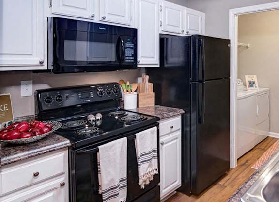 A kitchen with black appliances and white cabinets at Huntington Chase Apartments, Warner Robins, GA