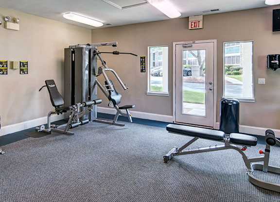 A gym with a variety of equipment including a squat rack, a leg press machine, and a bench press.