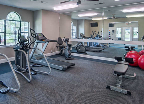 A gym with treadmills, elliptical machines, and other exercise equipment.