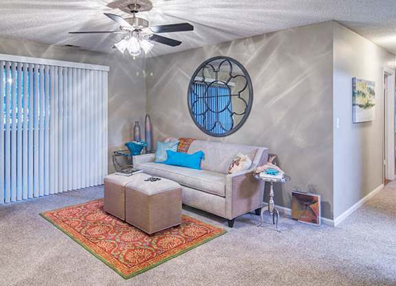 A living room with a sofa, armchair, and a rug.
