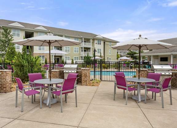 Outdoor grilling area with dining tables and umbrellas at Colony at Centerpointe Apartments, Midlothian, Virginia