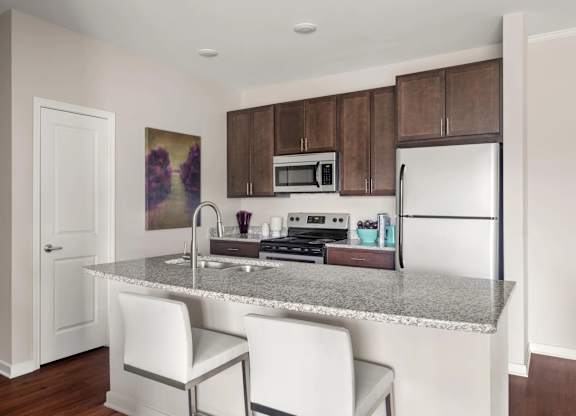Modern kitchen with island seating and granite countertops at Colony at Centerpointe Apartments, Midlothian, 23114