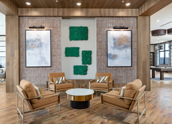 a lobby with a table and chairs and two paintings on the wall at The Flats at Southlawn Apartments, Lawrenceville