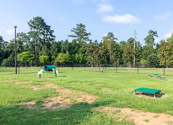 A baseball field with a green bench and a green trash can.