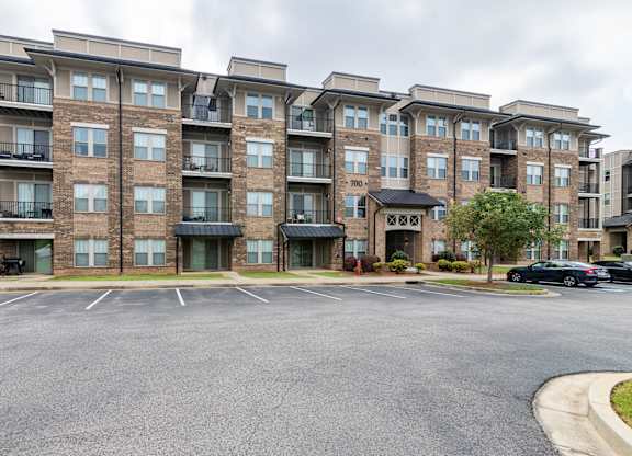A large apartment complex with a parking lot in front.
