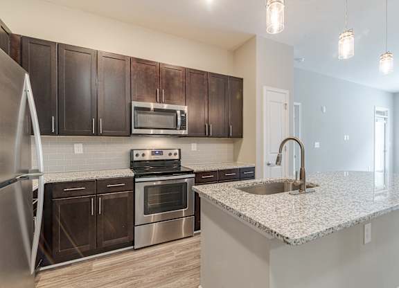 A kitchen with a stove, oven, refrigerator, and microwave.