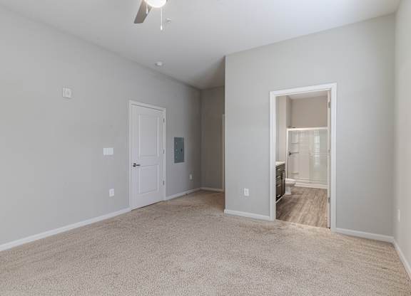 A spacious room with a carpeted floor and a ceiling fan.