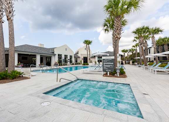 A pool surrounded by palm trees and lounge chairs.