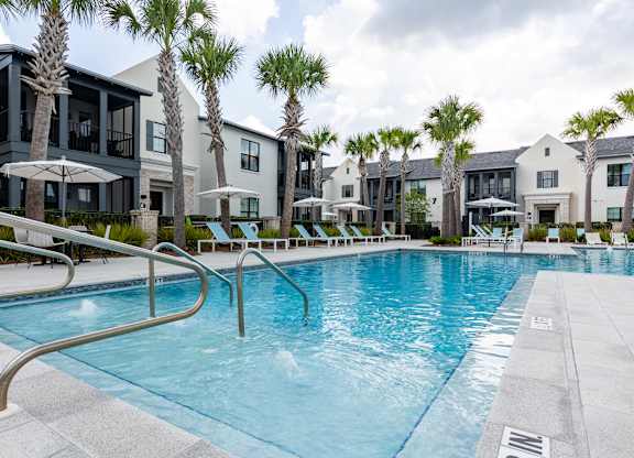 A swimming pool surrounded by palm trees and buildings.