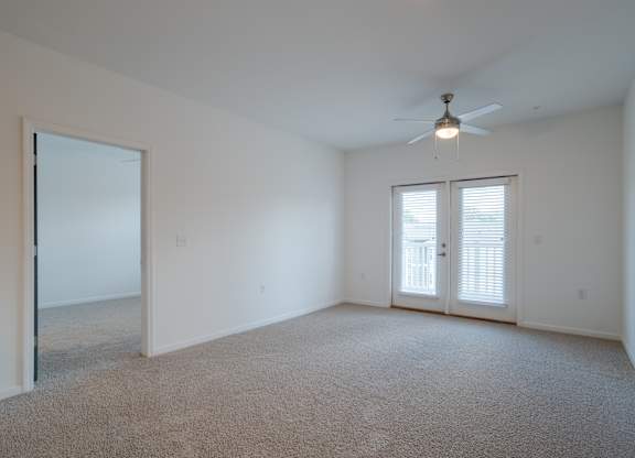 A room with a ceiling fan and carpeted floor.