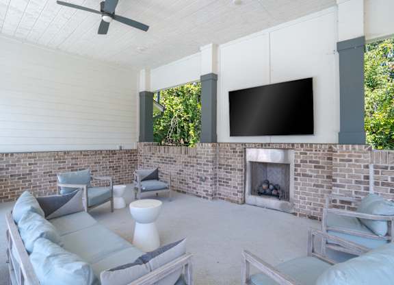 A modern living room with a brick fireplace and a flat screen TV mounted on the wall.