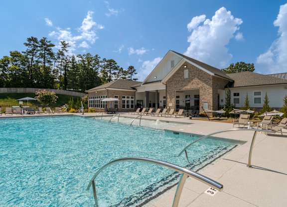 A large swimming pool in front of a building with a sunny sky.