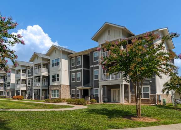 A large apartment complex with a tree in front of it.