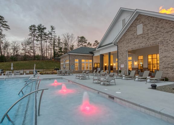 the pool is lit up at dusk next to a brick building at Retreat at Arden Farms, Arden