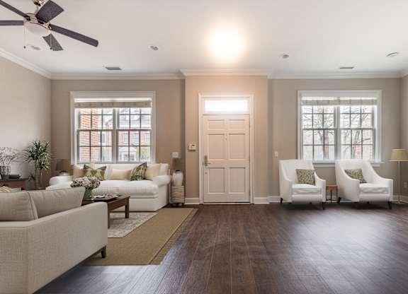 A living room with a white couch, two chairs, and a ceiling fan.