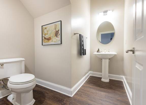 A bathroom with a toilet, sink, and mirror.