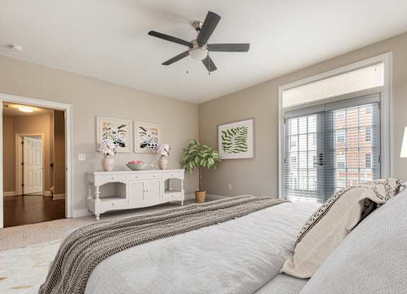 A bedroom with a large bed and a ceiling fan.