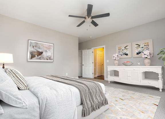 A bedroom with a bed, a fan, and a painting on the wall.