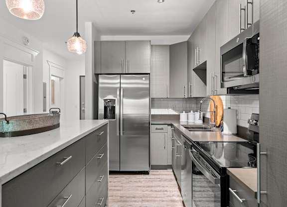 A modern kitchen with stainless steel appliances and a marble countertop.