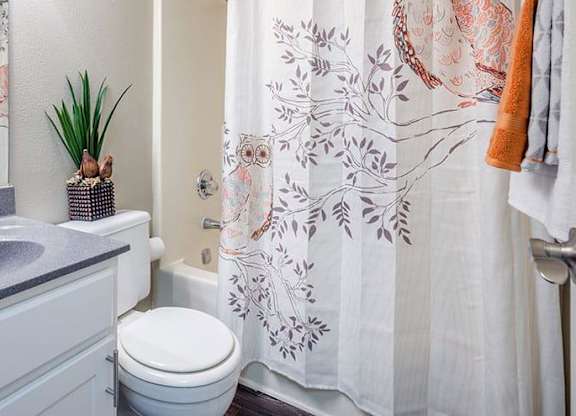 A bathroom with a toilet, sink, and shower curtain. at Woodwinds, Aiken, SC, 29803