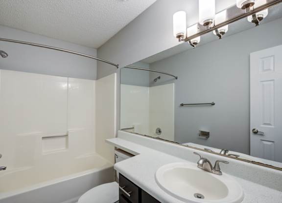 A white bathroom with a toilet, sink, and bathtub at Southland Station Apartments in Warner Robins, GA