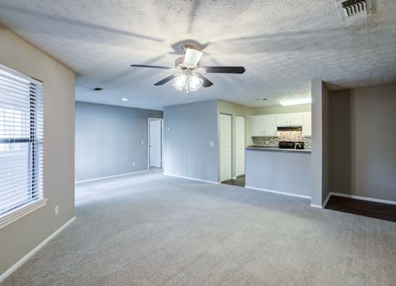 A spacious room with a ceiling fan and a window with blinds at Southland Station Apartments in Warner Robins, 31088