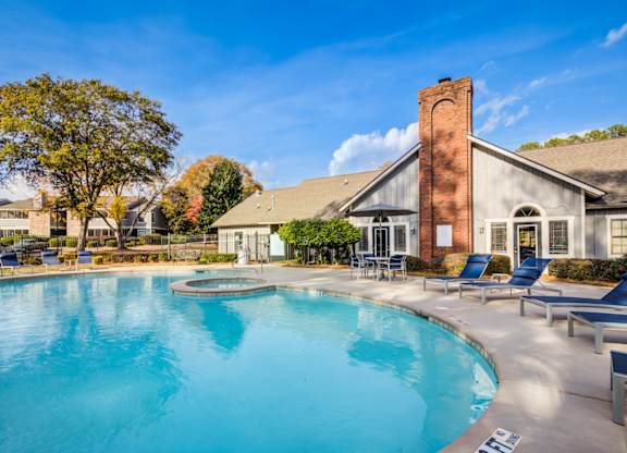 A large swimming pool in front of a building with a brick chimney at Southland Station Apartments in Warner Robins, Georgia