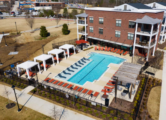 an aerial view of the resort style pool with red lounge chairs and umbrellas at The Flats at Southlawn Apartments, Lawrenceville, 30046