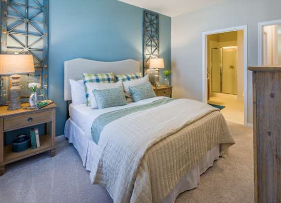 A bedroom with a bed, nightstand, and a wooden cabinet.