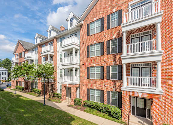 A red brick apartment building with white balconies and black shutters.
