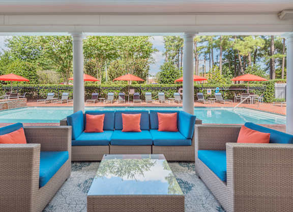 A patio with a pool and a table with chairs.