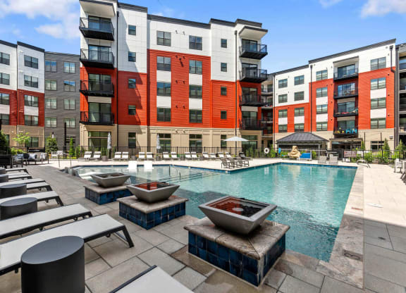 an outdoor pool with lounge chairs and fire pits at the bradley braddock road station at Tapestry West, Richmond Virginia