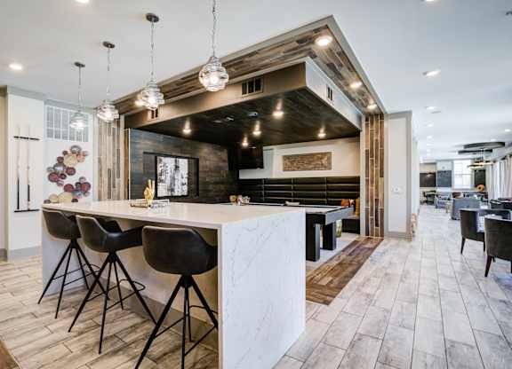 A modern kitchen with a white marble island and dark wood flooring.