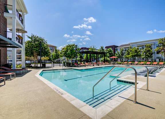 A swimming pool surrounded by a fence and a building in the background.