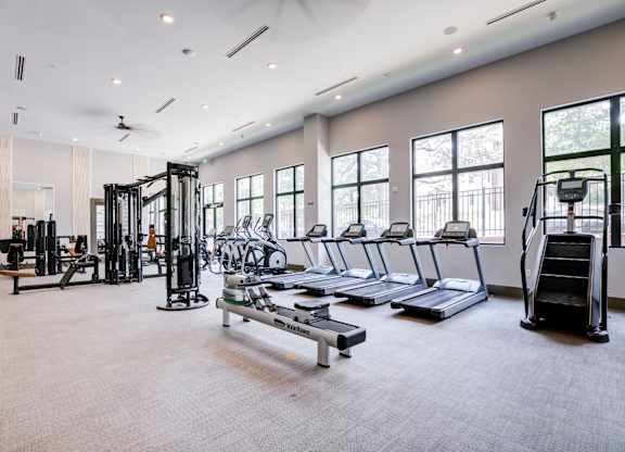 A spacious gym with treadmills, weights, and a fan.