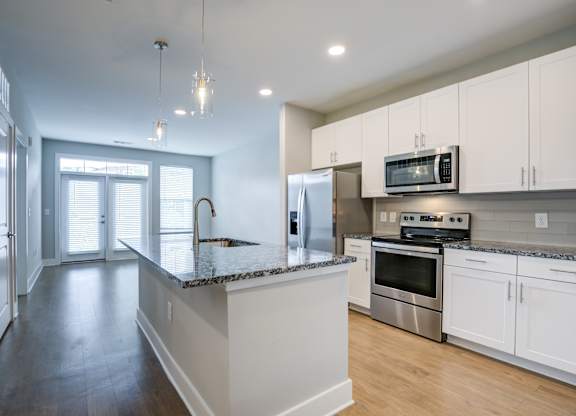 A kitchen with white cabinets and a granite countertop.