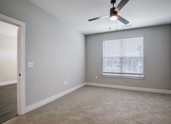 A room with a ceiling fan and a window with blinds.