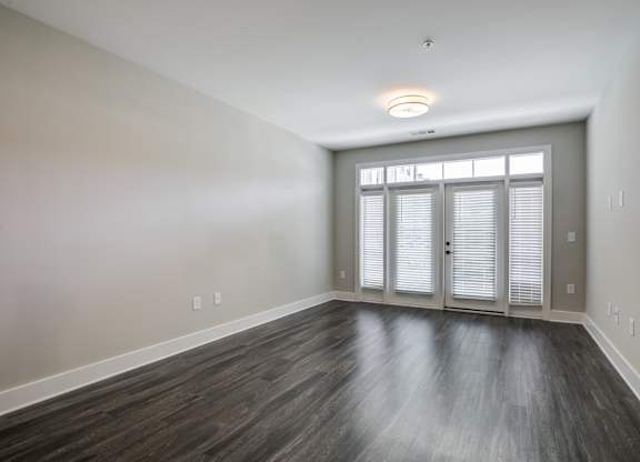 A room with wooden flooring and a window with blinds.