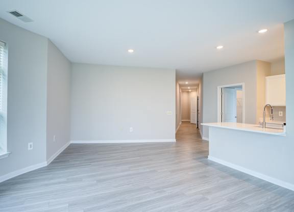 A spacious room with a window on the left and a door on the right.