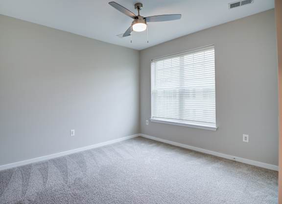A room with a ceiling fan and a window with blinds.
