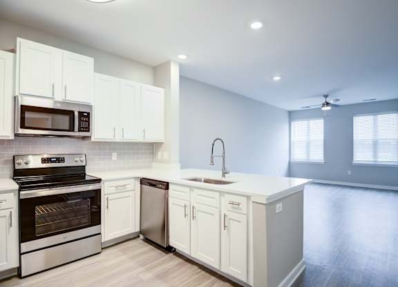 A modern kitchen with white cabinets and stainless steel appliances.