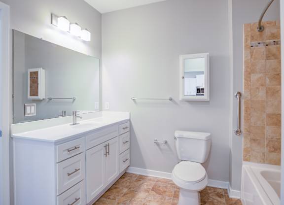 A white bathroom with a toilet, sink, and mirror.