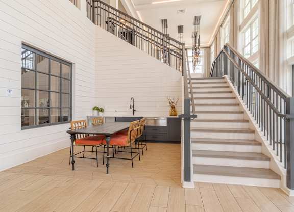 A dining table with chairs is in a room with a staircase.
