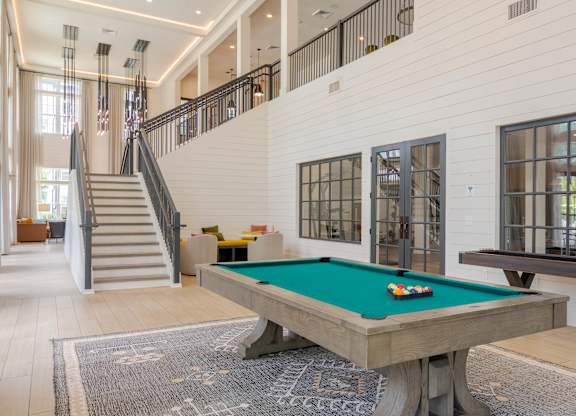 A pool table in a room with a staircase.