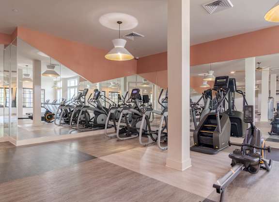 A gym with a variety of exercise equipment including treadmills, stationary bikes, and elliptical machines.