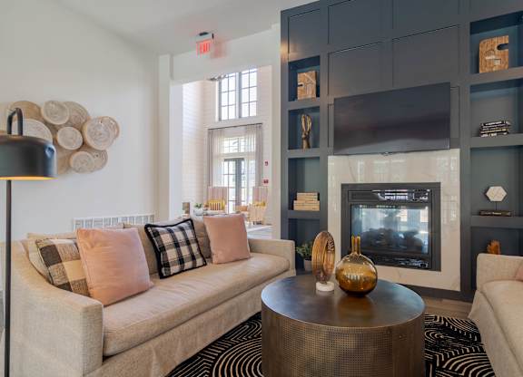 A living room with a beige couch, a coffee table, and a fireplace.