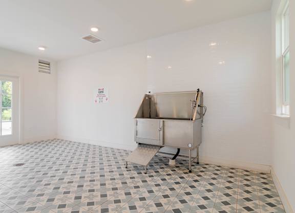 A large empty room with a tiled floor and a stainless steel appliance.