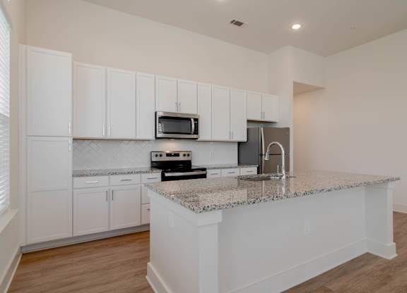 A kitchen with white cabinets and a granite countertop.